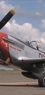 Vintage Mustang P-51 with red nose against a cloudy sky.