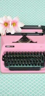 Vintage pink typewriter with flowers on a patterned background.