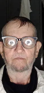 Elderly man with reflective glasses in a vintage portrait.