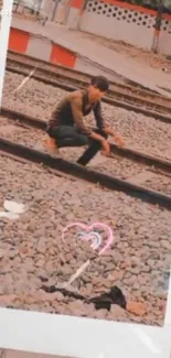 Person seated alone on railway tracks with heart overlay in vintage photo style.