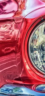 Close-up of red vintage car with intricate chrome details and shiny finish.