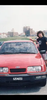 Vintage red car with urban background and person posing.