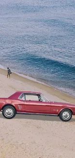 Vintage red car parked on a sandy beach with ocean waves in the background.