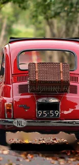 Vintage red car on a leafy forest road, capturing classic elegance.