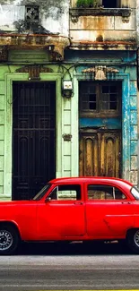 Vintage red car parked on an old street with rustic buildings.