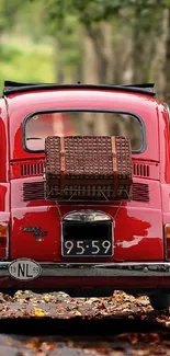 Vintage red car on an autumn road with falling leaves.