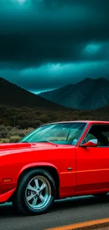 Vintage red muscle car on a road with mountains and stormy sky in background.