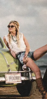 Vintage car and woman in bohemian attire on a sandy road.