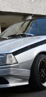 Vintage silver coupe car parked outdoors with sleek design.