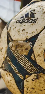 A vintage soccer ball with Adidas branding and worn textures in beige hues.