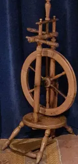 Vintage wooden spinning wheel against a blue curtain.