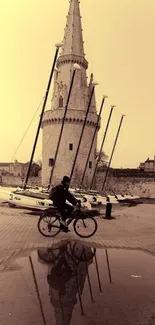 Cyclist in a sepia-toned street near a historic tower.