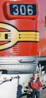 Vintage red train engine with child standing in front.