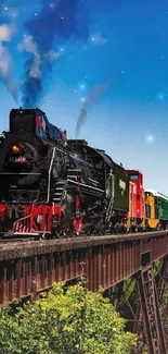 Steam train crossing a bridge over lush green landscape under blue sky.