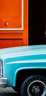 A vintage truck parked in front of a vivid orange wall.