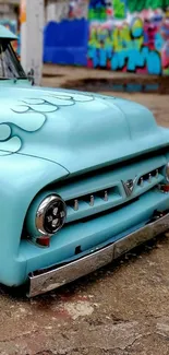 Vintage turquoise truck with graffiti background.