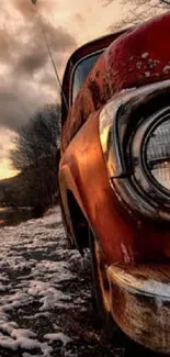 Vintage truck on snowy riverbank with sunset sky.