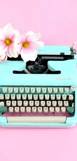 Vintage blue typewriter with pink flowers on a soft pink background.