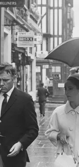 Black and white vintage scene with couple under umbrella.