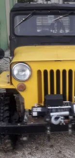 Vintage yellow Jeep parked outdoors, in front view.