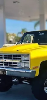 Vintage yellow truck at sunny gas station with palm trees.