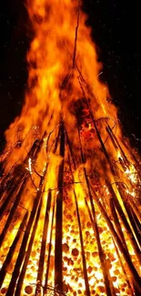 Blazing bonfire with vivid orange flames and burning sticks at night.