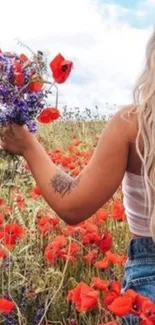 A woman in a field holding a bouquet of wildflowers under a cloudy sky.