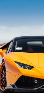 Bright orange sports car with clear blue sky background.