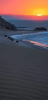 Vivid sunset over a tranquil beach with orange sky and blue ocean waves.