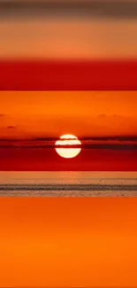 Vibrant sunset over calm ocean with orange-red hues and serene horizon.