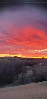 Vivid orange sunset over rolling hills landscape.