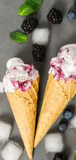 Ice cream cones with berries and mint on gray background.