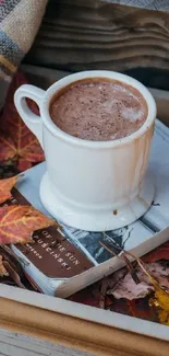 A cozy scene with a coffee cup and autumn leaves on a book.