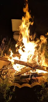 Glowing campfire with flames at night outdoors.