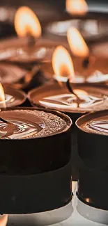 Close-up of cozy candles with glowing flames on a dark background.