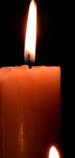 A candle with a warm, glowing flame against a dark background.