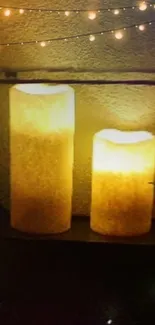 Glowing candles on shelf with string lights creating warm ambiance.