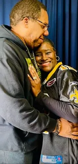 Couple embracing in sports jerseys against a navy blue backdrop.