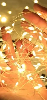 Hands holding glowing fairy lights with a warm yellow hue.