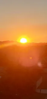 Sunset casting an orange glow over a suburban neighborhood with hills in the background.