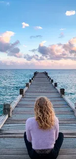 A serene wooden pier extending into a calm ocean under a pastel sky.