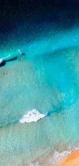 Aerial view of turquoise ocean waves meeting sandy beach.