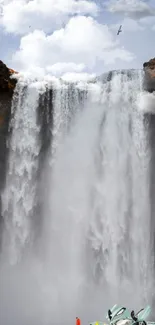 Waterfall with sports car in foreground against blue sky.