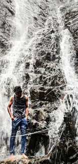 Man standing near a large rocky waterfall displaying natural beauty.