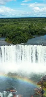 Waterfall with rainbow over lush green forest.