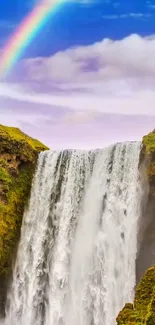 Waterfall cascading with rainbow in the sky above lush landscape.