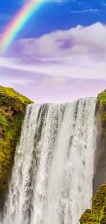 Waterfall with a rainbow over lush greenery and blue skies.