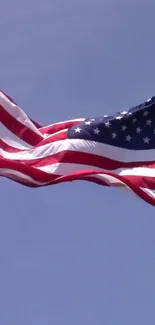 American flag waving against clear blue sky background.