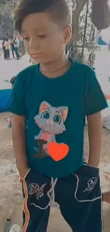 Child in blue shirt with cartoon cat design in an outdoor setting.