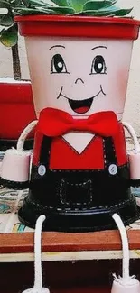 Whimsical planter with smiling face and red accents on a decorative table.